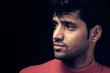 Portrait of young Indian man over dark