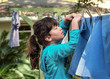 Little girl hanging laundry on the clothesline outdoors