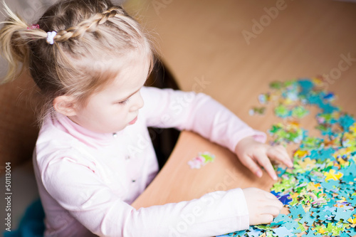 Photo: Cute little girl solving puzzles Cute little girl solving puzzles