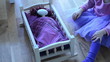 little girl cradled her doll lying on wooden bed