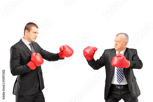 Photo: Angry mature boss and young businessman with red boxing gloves Angry mature boss and young businessman with red boxing gloves