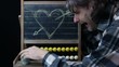 end of love concept, man erasing an heart sketch on chalkboard