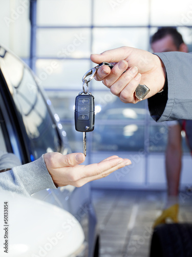 Photo: Key delivery between customer and mechanic in a garage Key delivery between customer and mechanic in a garage