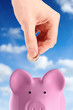 hand putting a coin into piggy bank