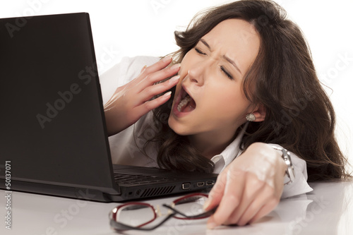 Photo: sleepy secretary on her laptop in the workplace on white backgro sleepy secretary on her laptop in the workplace on white backgro
