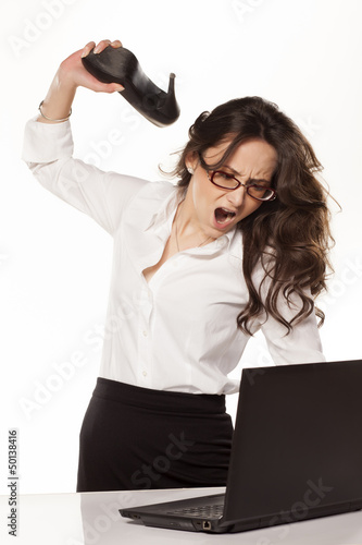 Photo: nervous and angry business woman destroys her laptop with high h nervous and angry business woman destroys her laptop with high h