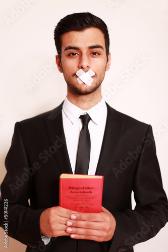 Photo: Mann mit Pflaster auf Mund und Gesetzbuch Mann mit Pflaster auf Mund und Gesetzbuch