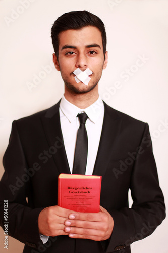 Photo: Mann mit Pflaster auf Mund und Gesetzbuch Mann mit Pflaster auf Mund und Gesetzbuch