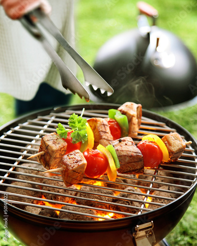 Photo: Person turning kebabs on a barbecue Person turning kebabs on a barbecue