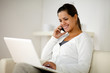 Woman speaking on cellphone in front of laptop