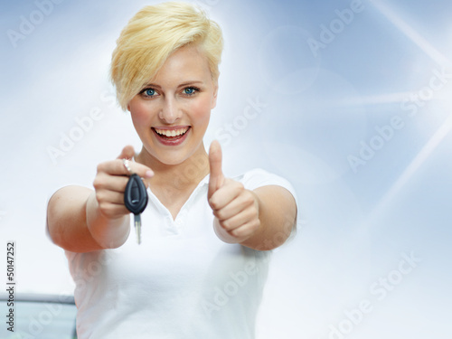 Photo: Pretty blonde woman proudly presents the key of her new car Pretty blonde woman proudly presents the key of her new car