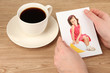 Photo in hands and cup of coffee on wooden table
