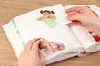 Photos in hands and photo album on wooden table