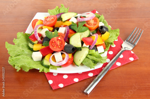 Photo: Tasty Greek salad on wooden background Tasty Greek salad on wooden background