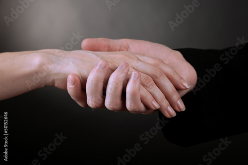 Photo: Priest holding woman hand, on black background Priest holding woman hand, on black background