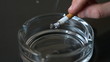 Hand tipping ash into empty ashtray