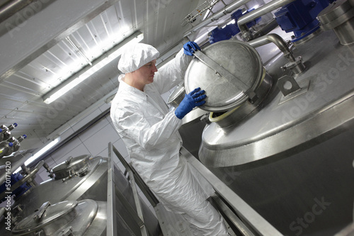 Photo: worker in apron and cap, controlling industrial process worker in apron and cap, controlling industrial process