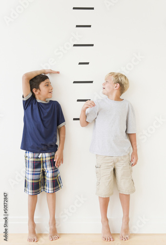 Photo: Boys measuring themselves against marks on wall Boys measuring themselves against marks on wall