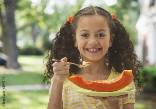 Photo: Hispanic girl eating cantaloupe Hispanic girl eating cantaloupe