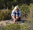 cool senior woman relaxing by herself on a stone in the woods