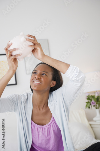 Photo: Black woman trying to get money out of piggy bank Black woman trying to get money out of piggy bank