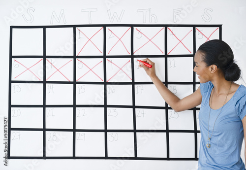 Photo: Black woman marking the days off calendar Black woman marking the days off calendar