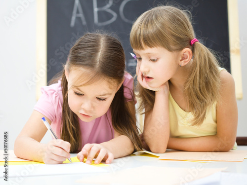 Photo: Little girls are writing using a pen Little girls are writing using a pen
