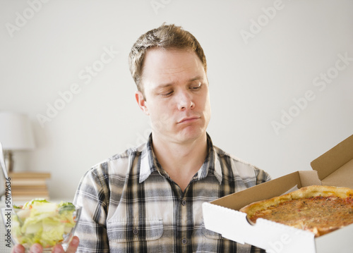 Photo: Caucasian man looking at pizza in box Caucasian man looking at pizza in box