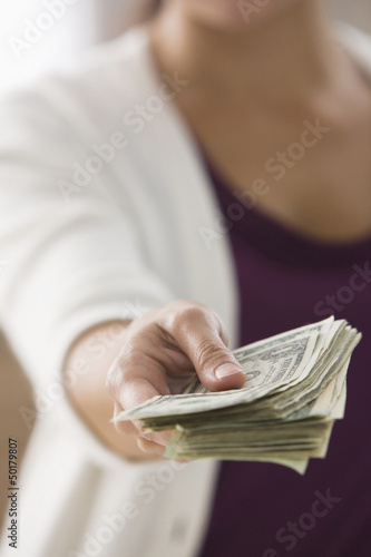 Photo: Mixed race woman holding out dollar bills Mixed race woman holding out dollar bills