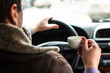A man sitting in a car and holding a cup of coffee