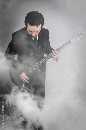 Photo: guitarist on stage full of smoke, man with black suit and guitar guitarist on stage full of smoke, man with black suit and guitar