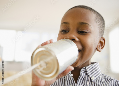 Photo: Black boy talking into tin can phone Black boy talking into tin can phone