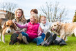 Photo: Family sitting with dogs together on a meadow Family sitting with dogs together on a meadow