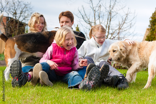Photo: Family sitting with dogs together on a meadow Family sitting with dogs together on a meadow