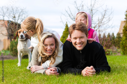 Photo: Family sitting with dogs together on a meadow Family sitting with dogs together on a meadow