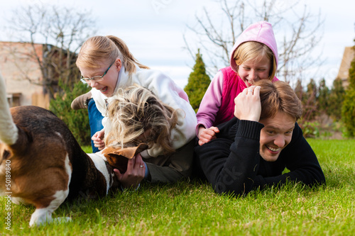 Photo: Family sitting with dogs together on a meadow Family sitting with dogs together on a meadow