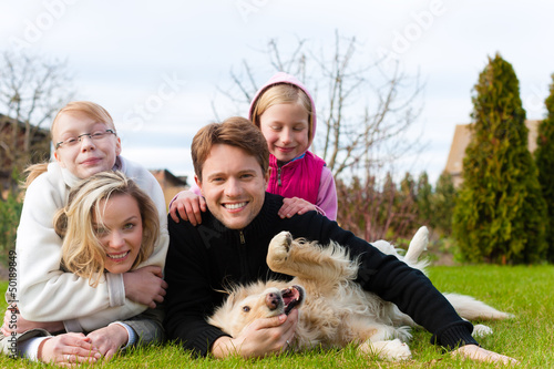 Photo: Family sitting with dogs together on a meadow Family sitting with dogs together on a meadow