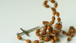 Rosary beads falling on white surface