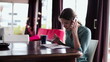 Young businesswoman with cellphone and documents working in home