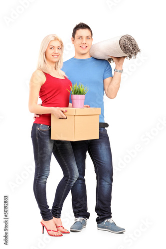 Photo: Full length portrait of a young male and female holding a moving Full length portrait of a young male and female holding a moving