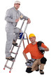 Painter on a ladder and crouching electrician
