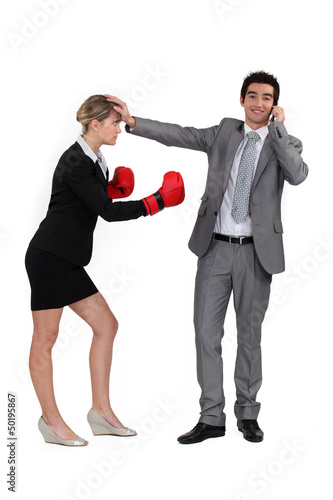 Photo: man on the phone and woman with boxing gloves man on the phone and woman with boxing gloves