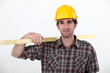A carpenter carrying a plank.