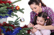 Mom and daughter decorating the Christmas tree