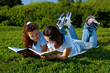Two girls reading books outside in a park