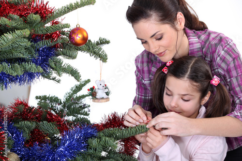 Photo: Mom and daughter decorating the Christmas tree Mom and daughter decorating the Christmas tree