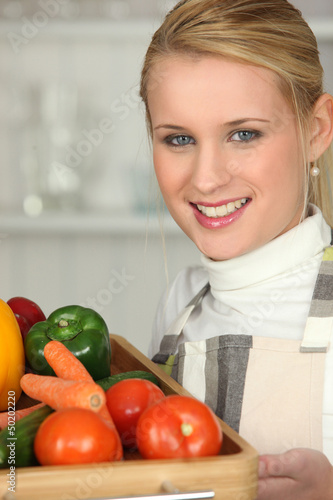 Photo: Young woman with a tray of fresh vegetables Young woman with a tray of fresh vegetables