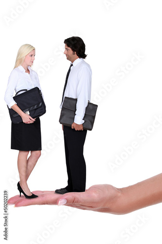 Photo: Business couple standing on a woman's hand Business couple standing on a woman's hand