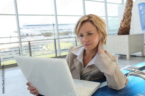 Photo: Woman with laptop waiting in airport Woman with laptop waiting in airport