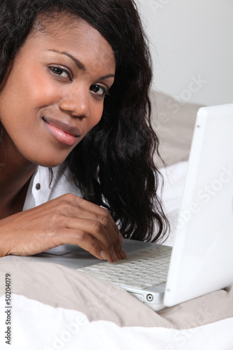 Photo: Woman using a laptop in bed Woman using a laptop in bed